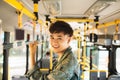 Asian man taking public transport, standing inside bus. Royalty Free Stock Photo