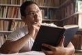 Asian man thinking while reading book, education concept, learning studying in library