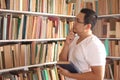 Asian man thinking to choose book to read, picking book in bookshelf, education concept, learning studying in library, happy Royalty Free Stock Photo