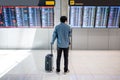 Asian man tourist at arrival departure board in airport Royalty Free Stock Photo