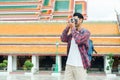 Asian man tourist walk taking photo with film camera at Wat Suthat Thepwararam Ratchaworawihan Bangkok, Thailand, Solo travel and