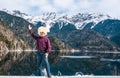 An Asian man in a traditional Caucasian white sheepskin hat raised his hand in greeting as a backdrop of a beautiful mountain