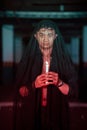 an Asian man with a transparent hood covered in blood holds a candle in his hand with a very scary expression