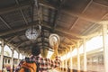 Asian man traveler with backpack holding hat and looking at clock in train station Royalty Free Stock Photo