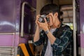 An Asian man traveler backpacker is taking pictures with his camera while getting off the train Royalty Free Stock Photo