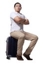 Asian man traveler sitting on his suitcase luggage, waiting gesture, wearing casual shirt and backpack, full length portrait Royalty Free Stock Photo