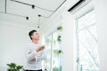 Asian man is turning air condition by remote control and smiling Royalty Free Stock Photo