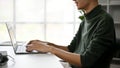 An Asian man typing on keyboard, using a laptop computer at his desk in a modern office Royalty Free Stock Photo