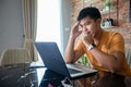 Asian man uses a notebook computer and works hard and meeting at home and he is stressed and Headache Royalty Free Stock Photo