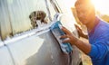 Asian man using blue sponge with soap to washing the car at outdoor in sunset time Royalty Free Stock Photo