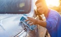 Asian man using blue sponge with soap to washing the car at outdoor in sunset time Royalty Free Stock Photo