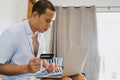 Asian man using credit card Data entry to laptop at home, personal finance and financial technology concept