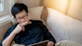 Asian man using digital tablet on bed in bedroom Royalty Free Stock Photo