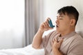 Asian man using inhaler sitting in bed at bedroom Royalty Free Stock Photo