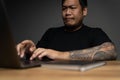 Asian man using laptop with focusing face on wooden table with laptop. Concept about works at home