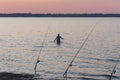 Asian man wade fishing spin casting near row of poles at Lavon Lake near Dallas, Texas, USA