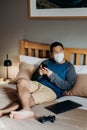 Asian man weared medical mask. Sitting and using cell phone in bedroom