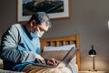 Asian man weared medical mask. Sitting and using laptop in bedroom