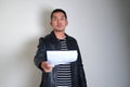 Asian man wearing black leather jacket showing fierce expression while handed letter Royalty Free Stock Photo