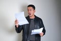 Asian man wearing black leather jacket showing shocked expression while read something Royalty Free Stock Photo