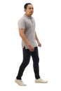 Asian man wearing casual grey shirt black denim and white shoes, walking forward, side view, happy confidence expression. Full Royalty Free Stock Photo