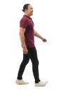 Asian man wearing casual maroon red shirt black denim and white shoes, walking forward, side view, happy confidence expression. Royalty Free Stock Photo