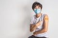 Asian man wearing face mask with a smile on his face showing his vaccinated arm. vaccination, recommended inoculation concept