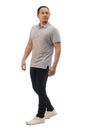 Asian man wearing grey shirt black denim and white shoes, walking forward, side view, happy confidence expression. Full body Royalty Free Stock Photo