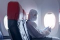 Asian man is wearing protective suit , PPE suit in airplane , safety travel concept