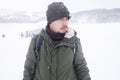 Asian man wearing a sweater jacket stands in a ski resort. In the middle of snow mountain