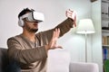 Asian man wearing VR goggles while playing video games with hands reaching out to touch something in virtual world Royalty Free Stock Photo