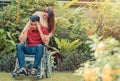 Asian Man in a wheelchair and Unhappy and painful. A woman standing behind the wheelchair and is encouraging her husband, whose fe