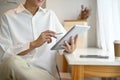 An Asian man in white shirt using his digital tablet while relaxing in a coffee shop Royalty Free Stock Photo