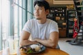 Asian man in white t-shirt waiting for someone to meet at the restaurant. Royalty Free Stock Photo