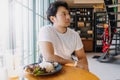 Asian man in white t-shirt waiting for someone to meet at the restaurant. Royalty Free Stock Photo