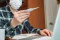 An Asian man who is self-isolated and working from home because of a massive pandemic. A man holding a thermometer to measure body