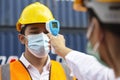 Asian man worker wearing face mask checking fever by digital thermometer before entering the work for protecting from covid, covid Royalty Free Stock Photo