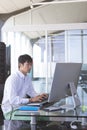 Asian man working on desktop computer in modern office, focusing on task, copy space