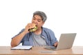 Asian man working and eating a burger on the office desk. Concept of a busy businessman cannot work-left balance and not taking Royalty Free Stock Photo