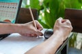 Asian man wrote the budget with a pencil in his left hand side to the paper, At the outdoor and green leaf behind Royalty Free Stock Photo