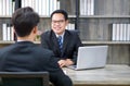 Asian manager in the black suit interviewed the applicant with a smile. The atmosphere of job interview in the modern office