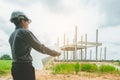 Asian manager of civil engineer architects in white helmet safety on construction site stand to check a plan and project