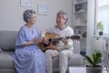 Asian mature male and female singing favorite song while playing on guitar at home