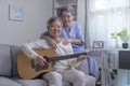 Asian mature male and female singing favorite song while playing on guitar at home