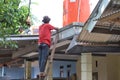 Asian mature man is repairing water place on roof of house