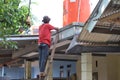 Asian mature man is repairing water place on roof of house.