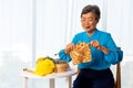 Asian mature senior woman knitting wool clothes and sitting on wooden chair