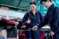 Asian mechanic man in uniform welding car body panel vehicle, beautiful woman technician coworker giving thump up, auto mechanic