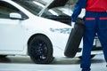 Asian mechanic in uniform Standing holding a car tire is changing a wheels tires while working in car repair center