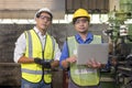 Asian mechanical engineer operating industrial lathe machine. Asian male Industrial engineer with laptop in safety jacket at heavy Royalty Free Stock Photo